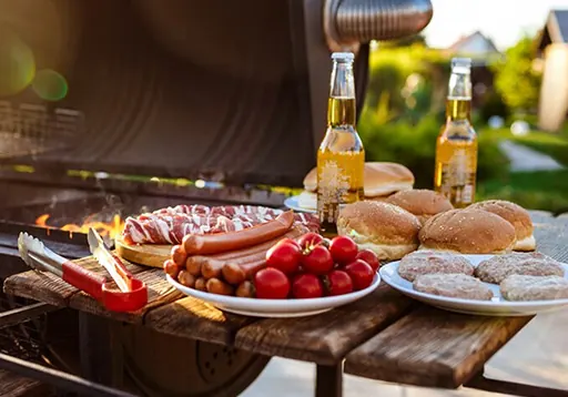 Barbecue met vleespakket, broodjes en tomaten